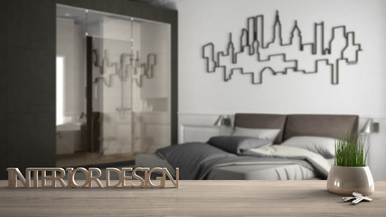 Wooden table, desk or shelf with potted grass plant, house keys and 3D letters making the words interior design, over blurred minimalist bedroom, project concept copy space background
