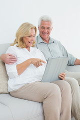 Relaxed senior couple using digital tablet on sofa