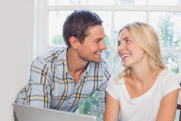 Smiling young couple looking at each other at home