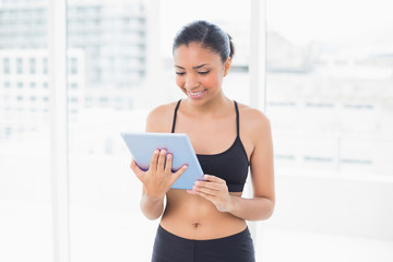 Concentrated dark haired model in sportswear using a tablet pc