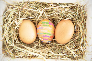 Happy easter in different languages against three eggs in a basket