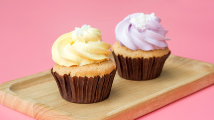 Cupcake on a wooden plate and pink background.