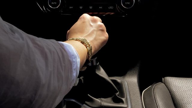 Hand of woman changing gear while driving car at sunset high shot