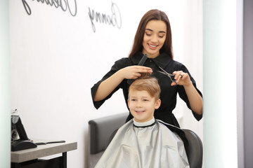 Professional female hairdresser working with little boy in salon