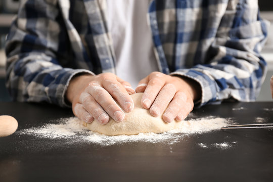 Man kneading dough on table covered with flour in kitchen