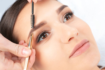 Young woman having professional eyebrow correction procedure in beauty salon