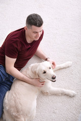 Handsome man with dog lying on carpet at home