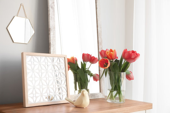 Modern room interior with mirror and flowers on table