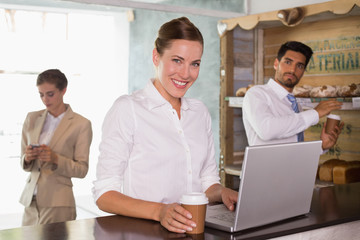 Businesswoman using laptop in office cafeteria