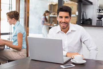 Smiling man using laptop in the coffee shop