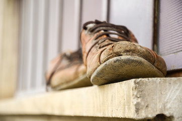 Muddy and old  shoes in front of the window, worker's shoes, labor, soreness,