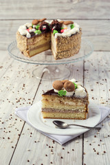 dark chocolate vegan cake with cream and caramel on wooden background