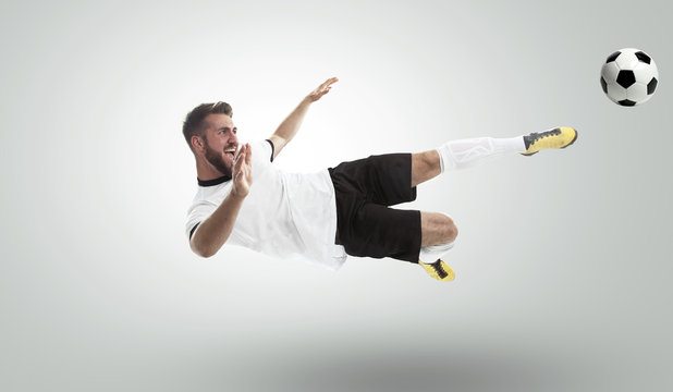 Fu&szlig;ballspieler schie&szlig;t ein Fu&szlig;ball. Freigestellt im Studio