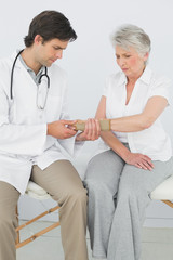 Male physiotherapist examining a senior womans wrist
