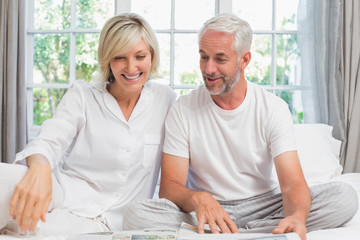 Smiling mature couple sitting on bed at home