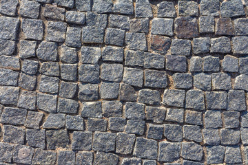 Stone pavement texture, granite cobblestoned pavement background, cobbled stone road regular shapes, abstract background of old cobblestone pavement close-up