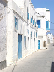 Fototapeta na wymiar Deserted street of Mahdia with blue doors and lattices on the windows