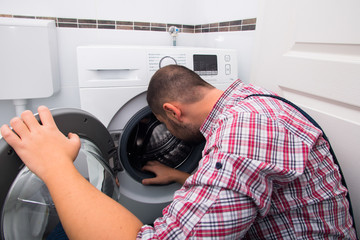 Handyman repairing washing machine in bathroom