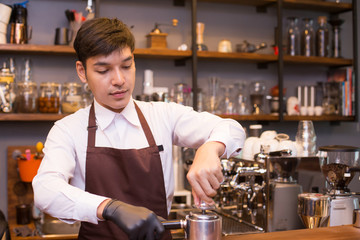 Asian male barista making coffee in coffee shop counter.  Barista male working at cafe. Man working with small business owner or sme concept.