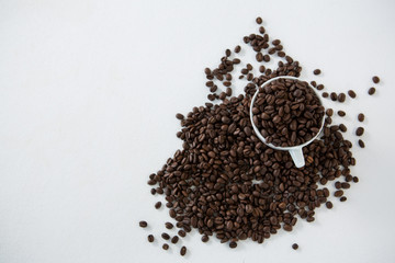Cup of coffee filled with roasted coffee beans