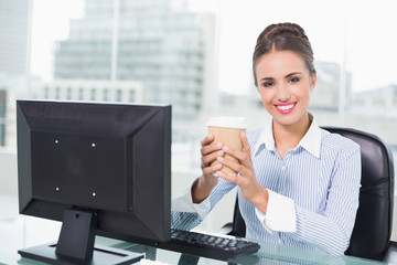 Smiling brunette businesswoman holding disposable cup