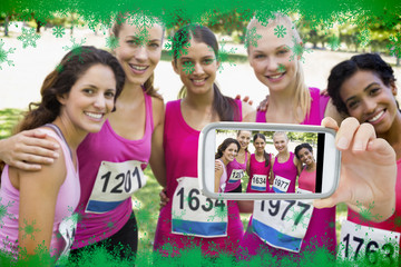 Hand holding smartphone showing confident female participants of breast cancer marathon