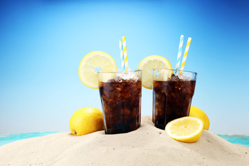 Softdrink with ice cubes, lemon and straw in glass.