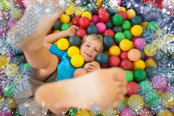 Fototapeta na wymiar Composite image of happy boy playing in ball pool against snow