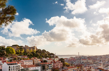 Fototapeta premium Old Lisbon oldtown panorama of Alfama. View to Saint George castle. Portugal cityscape with roofs. Tagus river. miraduro viewpoint