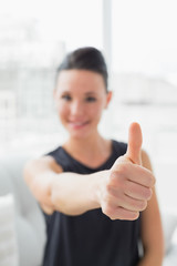 Blurred smiling well dressed woman gesturing thumbs up