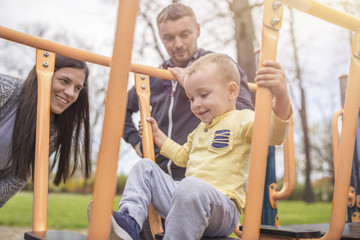 Parents having fun with their child in park playground