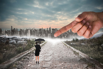 Giant hand pointing at young businesswoman holding umbrella against stony path leading to large city on the horizon