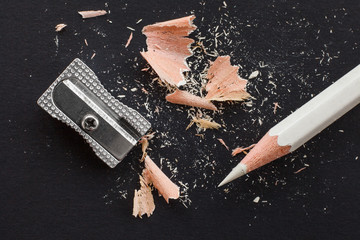 white wooden pencil, sharpener and pencil shavings on black - obrazy, fototapety, plakaty