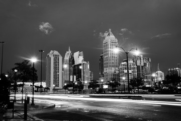 Illuminated Midtown in Atlanta, USA at night. Car traffic, illuminated buildings and dark sky. Black and white - obrazy, fototapety, plakaty