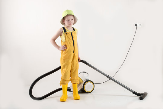 Happy child in yellow working overall with portable yellow-white vacuum cleaner with brush on white background.