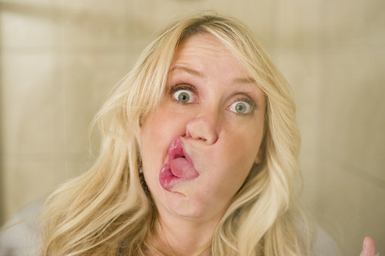 Blonde woman smashing face against window silly look