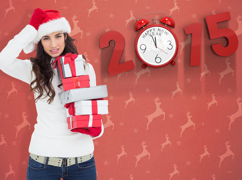 Stressed brunnette in santa hat holding gifts against orange reindeer pattern