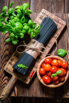 Ingredients for black spaghetti made of basil and tomatoes