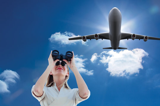 Businesswoman looking through binoculars against sky  - Powered by Adobe
