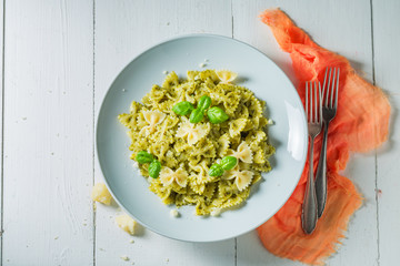 Tasty spaghetti with green pesto, parmesan and basil