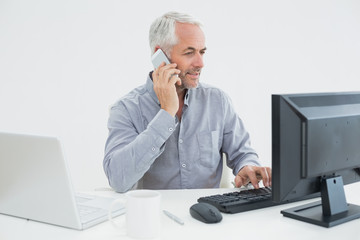 Businessman with cellphone, laptop and computer at desk