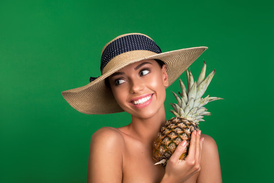 Portrait of smiling woman with headdress on head holding pineapple. Isolated on background