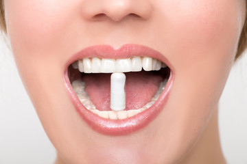 Naklejka premium Film tablet between the teeth of a woman
