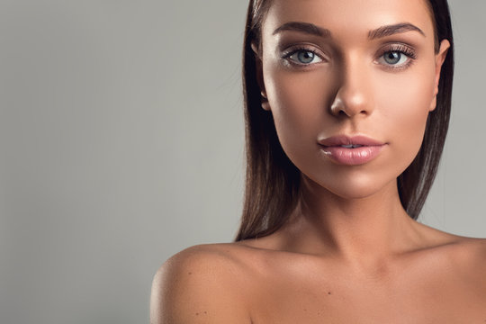 Portrait of well cared woman face with pensive look. Her shoulders are undressed. Copy space in left side. Isolated on background