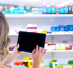 Rear view of woman using tablet pc against close up of shelves of drugs