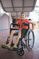 Obraz premium Portrait of cute boy sitting on wheelchair in corridor