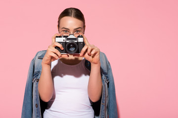 Portrait of cheerful young woman taking photo with inspiration. She is holding camera near her face. Copy space