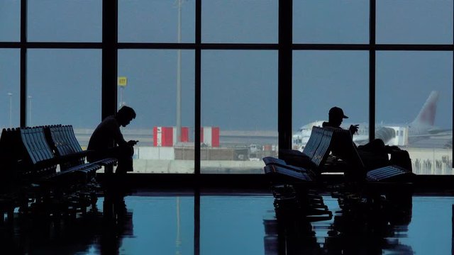 Waiting room in airport terminal with people silhouettes on the seats 
