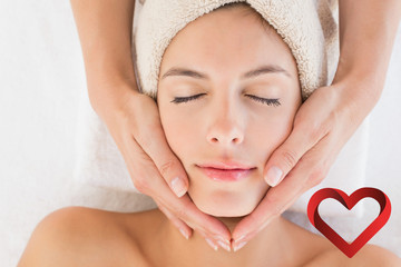 Attractive woman receiving facial massage at spa center against heart