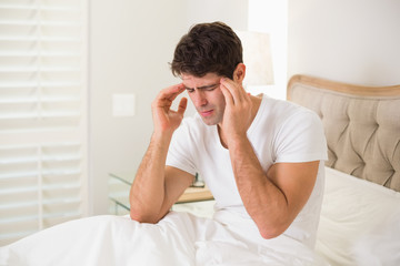 Young man suffering from headache in bed